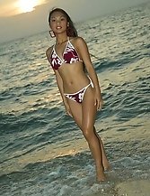 Sultry Asian model poses in the ocean water at sunset